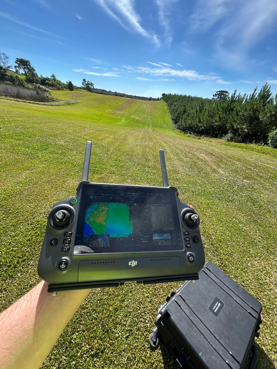 Engenheiro da aeropixel operando GNSS RTK em campo com drone ao fundo